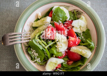 Épinards frais, salade de tomates et concombres garnies de fromage parmesan râpé. Banque D'Images