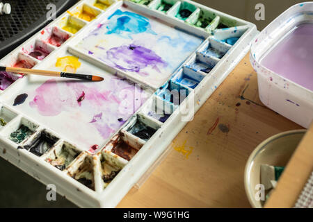 La palette de l'artiste avec des peintures à l'aquarelle et la peinture dans des puits. Banque D'Images