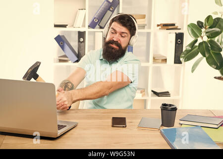 Décalage de l'ordinateur. Pour des raisons du retard de l'ordinateur. Comment fixer la traîne lente du système. La routine du bureau. Homme barbu bureau écouteurs swing marteau sur ordinateur. Connexion internet lente. Logiciel obsolète. Banque D'Images