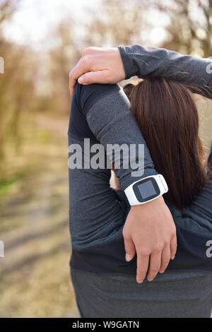 Smartwatch woman running avec moniteur de fréquence cardiaque. Libre de porter au poignet féminin montre sport smart activity tracker comme à l'extérieur au cours de séance de cardio. Fitness petite fille qui s'étend au cours de l'entraînement du triceps. Banque D'Images