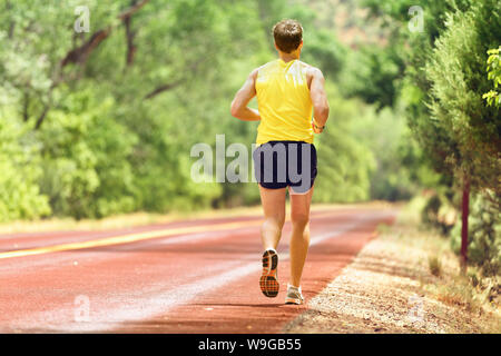 Running Man working out runner pour la remise en forme. Athlète masculin sur le jogging courir portant des chaussures de course de sport et des courts-circuits pour marathon. La pleine longueur du corps vue montrant l'arrière de s'enfuir. Banque D'Images