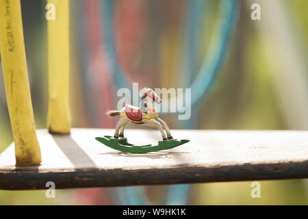 Cheval à bascule miniature en bois anciens lors d'une aire de jeux avec des balançoires corde colorée Banque D'Images