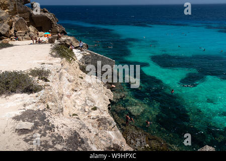 Favignana, Italie - Août 09, 2019 : la plage rocheuse de Bue Marino dans la magnifique île de Favignana dans une journée ensoleillée. Les gens sont de détente Banque D'Images