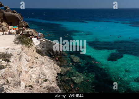 Favignana, Italie - Août 09, 2019 : la plage rocheuse de Bue Marino dans la magnifique île de Favignana dans une journée ensoleillée. Les gens sont de détente Banque D'Images