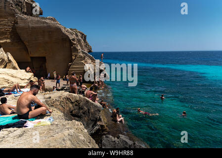 Favignana, Italie - Août 09, 2019 : la plage rocheuse de Bue Marino dans la magnifique île de Favignana dans une journée ensoleillée. Les gens sont de détente Banque D'Images