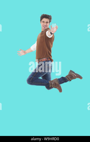 Jeune homme montrant le téléphone mobile transparent et le saut Banque D'Images