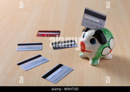 Credit card inserting into a piggy bank Stock Photo