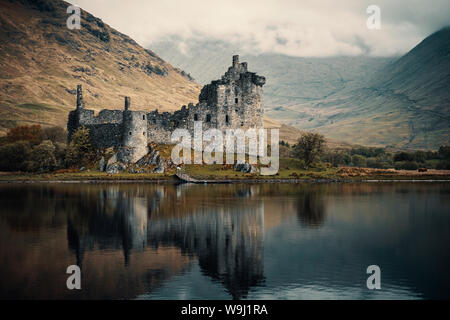 Le Château de Kilchurn reflétée dans un Loch Awe encore dans les montagnes de l'Ecosse avec nuages tôt le matin assis sur les collines au loin Banque D'Images