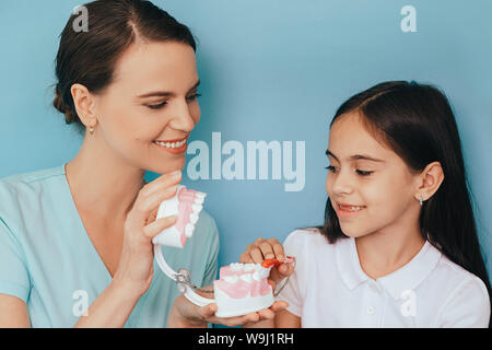 Mixed Race girl montrant comment brosser les dents de son dentiste, lors d'un rendez-vous chez le dentiste Banque D'Images