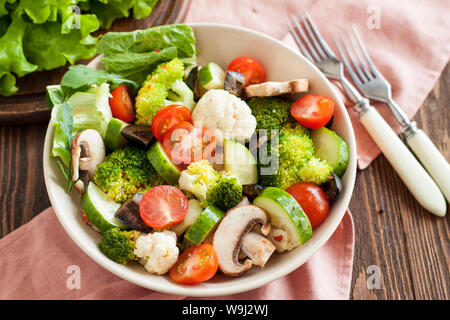 Savoureuse salade italienne avec des légumes marinés, champignons, tomates cerises et Parmesan sur fond de bois Banque D'Images