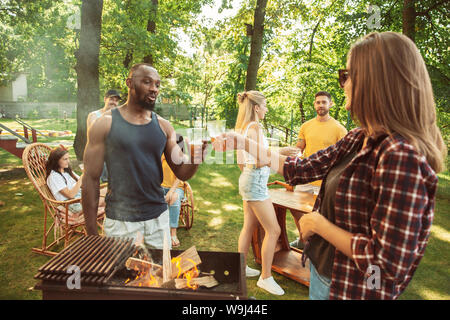 Groupe des amis de la bière et heureux d'avoir un barbecue de travail à jour ensoleillé. Ensemble de repos dans une forêt en plein air ou glade jardin. Célébrer et relaxant, laughting. Vie d'été, l'amitié concept. Banque D'Images