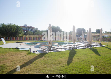 Piscine vide avec parasol et transats à matin d'été dans la cour à louer appartement. Banque D'Images