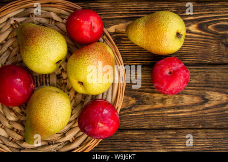Poires mûres et prunes rouges sur une table en bois, la composition d'été Banque D'Images