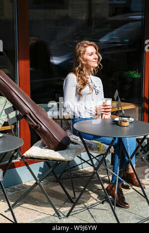 Fille assise avec un café dans la main et près de violon Banque D'Images