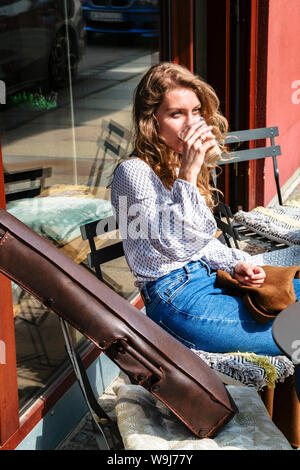 Fille assise avec un café dans la main et près de violon Banque D'Images