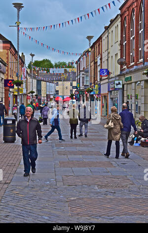 Une vue générale d'Adare Street, l'une des principales rues commerçantes du centre-ville. Les gens/ marchant le long d'acheteurs au-delà d'un musicien ambulant à capuchon isolés. Banque D'Images