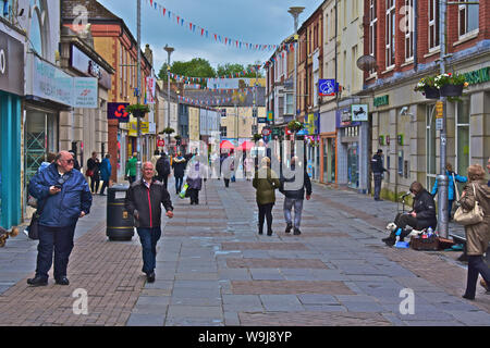 Une vue générale d'Adare Street, l'une des principales rues commerçantes du centre-ville. Les gens/ marchant le long d'acheteurs au-delà d'un musicien ambulant à capuchon isolés. Banque D'Images