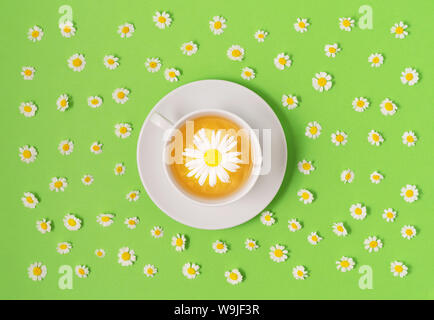 Tasse de thé de camomille fleurs avec des fleurs aux tons de vert sur la surface. Soins de santé et des aliments sains. Mise à plat. Banque D'Images