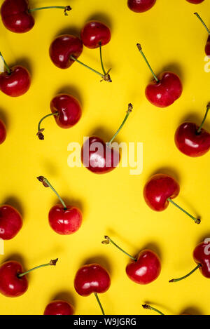 Bouquet de cerises fraîches sur fond jaune Banque D'Images