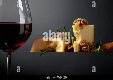 Fromage Maasdam aux noix, le romarin et le vin rouge sur un fond sombre. Copier l'espace. Banque D'Images