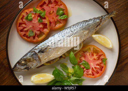 Un maquereau (Scomber scombrus), qui a été cuit en papillote et servi avec des tranches de tomate, basilic, huile d'olive et des quartiers de citron. C'est farci de Banque D'Images