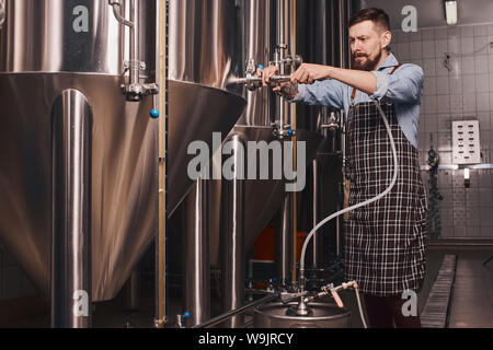 Beer maker se mélange à des types de bière dans le baril alors qu'il tente de faire d'autres choix flavoral. Banque D'Images