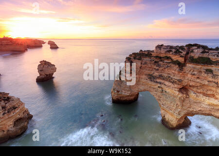Lever du soleil sur les falaises encadrées par de l'eau turquoise de l'océan, Praia da Marinha, Caramujeira, Municipalité de Lagoa, Algarve, Portugal, Europe Banque D'Images