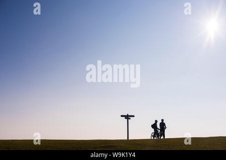 Les cyclistes prennent une pause sur le sommet d'une colline au coucher du soleil dans le Dorset, Angleterre, Royaume-Uni, Europe Banque D'Images