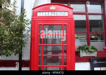 Image d'un téléphone rouge située en face du bâtiment blanc aux feuilles autour, à Knutsford Banque D'Images