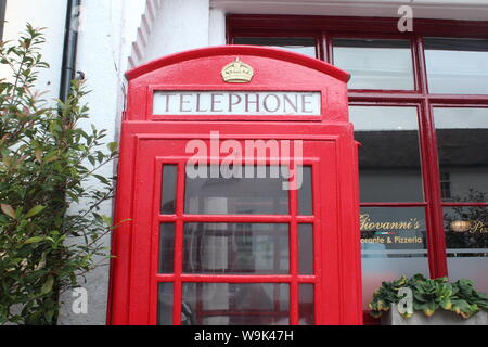 Image d'un téléphone rouge située en face du bâtiment blanc aux feuilles autour, à Knutsford Banque D'Images