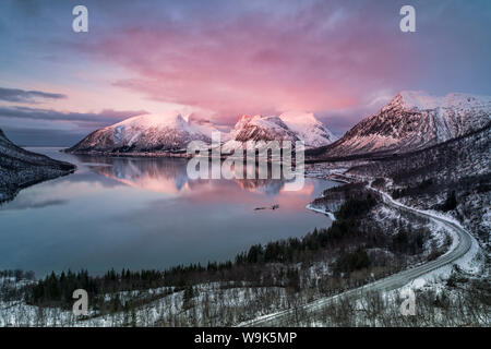 Ciel et nuages roses sur les pistes enneigées reflète dans la mer froide au coucher du soleil, Bergsbotn, Senja, comté de Troms, Norvège, Scandinavie, Europe Banque D'Images