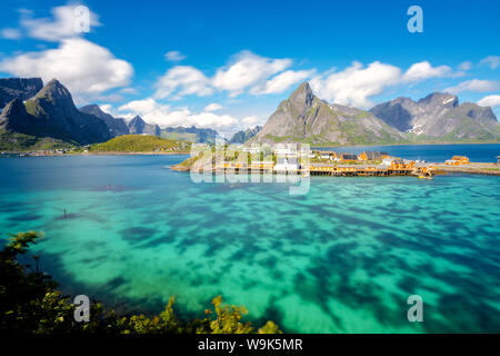 La mer turquoise entoure le typique village de pêcheurs entouré de pics rocheux, Sakrisoy, Reine, Moskenesoya, îles Lofoten, Norvège, Scandinavie Banque D'Images