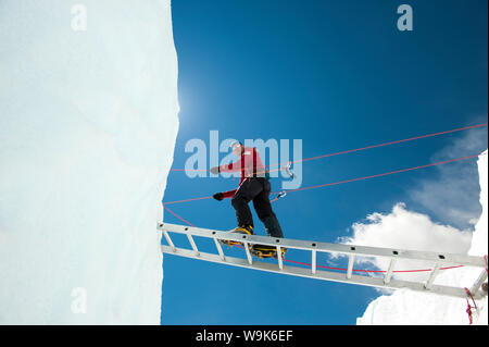 Un grimpeur sur Everest fait son chemin à travers une crevasse à l'aide d'une échelle temporaire, région de Khumbu, Népal, Asie Banque D'Images