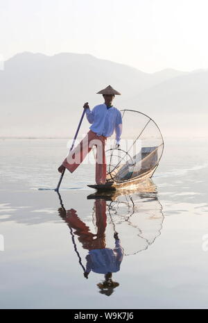 'Aviron' ethnie Intha jambe pêcheurs au coucher du soleil sur le lac Inle, qui pêchent avec des filets tendues sur des cadres en bambou conique, au Lac Inle, Myanmar Banque D'Images