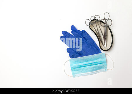 Instruments médicaux et chirurgicaux ciseaux et des gants en latex, dans un bol de rein isolé sur fond blanc Banque D'Images