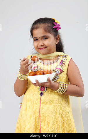 Girl eating Jamun Gulab and smiling Banque D'Images