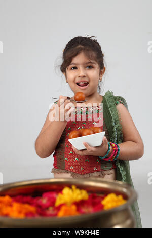 Girl eating Jamun Gulab and smiling Banque D'Images