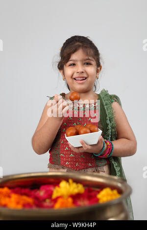 Girl eating Jamun Gulab and smiling Banque D'Images