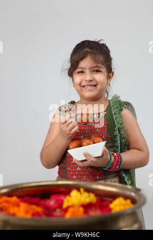 Girl eating Jamun Gulab and smiling Banque D'Images