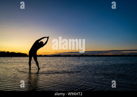 La pratique du yoga posture de l'arbre palm - sunrise silhouette d'un homme sur une plage du lac, Boyd Lake State Park dans le nord du Colorado Banque D'Images