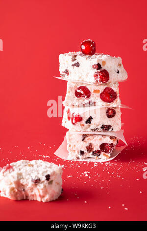 Dessert traditionnel de Noël australien, un Noël blanc Gâteaux, entassés dans une pile et un morceau mangé, sur un fond rouge. Les vacances d'hiver, les sucreries de fête Banque D'Images