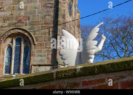 Un ange ou chérubin ailé memorial sur une tombe dans une église avec des ailes blanches et une main et doigt pointant vers le ciel Banque D'Images