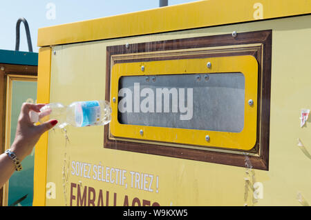 Ajaccio, Corse, 2019-08-France.. Main femme mise en bouteille d'eau en plastique dans le conteneur de recyclage, la rue Banque D'Images