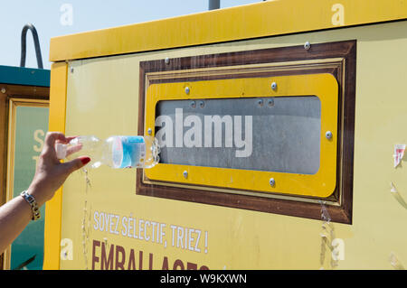 Ajaccio, Corse, 2019-08-France.. Main femme mise en bouteille d'eau en plastique dans le conteneur de recyclage, la rue Banque D'Images