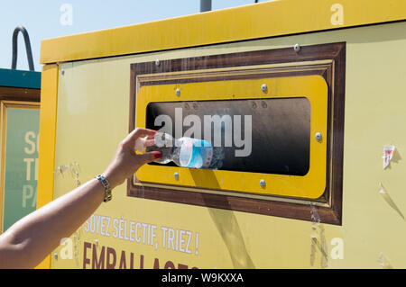 Ajaccio, Corse, 2019-08-France.. Main femme mise en bouteille d'eau en plastique dans le conteneur de recyclage, la rue Banque D'Images