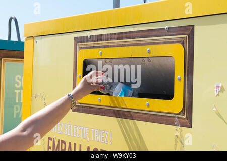 Ajaccio, Corse, 2019-08-France.. Main femme mise en bouteille d'eau en plastique dans le conteneur de recyclage, la rue Banque D'Images