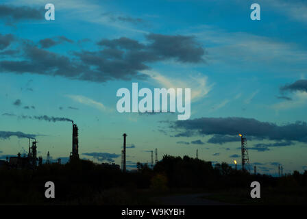 Paysage industriel de silhouette avec des torches et des colonnes de fractionnement dans le contexte d'un ciel sombre soir Banque D'Images