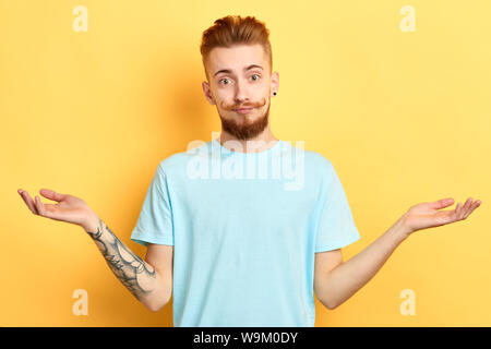 Young handsome man with moustache drôle à la caméra et à propager les mains. Isolé sur fond jaune.C'est un morceau de gâteau Banque D'Images