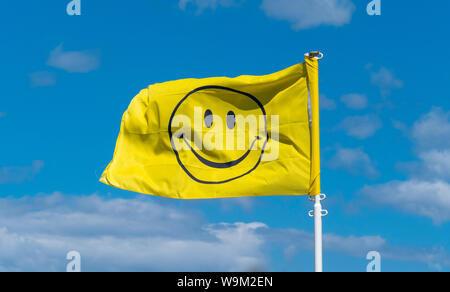 Le symbole de smiley drapeau jaune contre le ciel bleu Banque D'Images