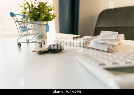 Achat de voiture concept. Vide panier , des clés de voiture, la calculatrice et l'ordinateur portable sur tableau blanc Banque D'Images